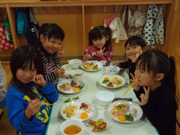 園児達が笑顔で美味しそうにお昼ご飯を食べている様子